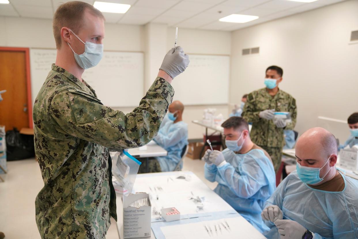 Navy personnel prepare doses of the COVID-19 vaccine before the opening of a mass vaccination site in the Queens borough of New York on Wednesday, Feb. 24, 2021.