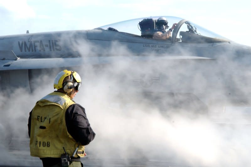 An Aviation Boatswain's Mate directs an F/A-18 Hornet into position to be launched from the flight deck aboard the aircraft carrier USS Harry S. Truman on March 20, 2003. On March 20, 2003, U.S.-led coalition forces begin military operations in Iraq. File Photo by Michael W. Pendergrass/U.S. Navy