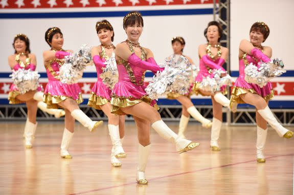 In this picture taken on March 26, 2016, members of the middle-aged and elderly women cheerleading group "Japan Pom Pom" perform during the national cheerleading and dance championship 2016 of the United Spirit Association (USA) Japan in Chiba, a suburb of Tokyo. Strutting her stuff in a gold-hemmed mini-skirt, white leather boots and shaking silver pom-poms, octogenarian Fumie Takino has discovered her elixir of youth -- cheerleading. Takino and her troupe of spirited grannies tweak the nose of old age, even if their rambunctious routine to the song "Dreamgirls" leaves them painfully out of breath and their pink tank tops dripping with sweat. / AFP / TORU YAMANAKA / TO GO WITH AFP STORY: "JAPAN-ELDERLY-CHEERLEADING" FEATURE by Harumi OZAWA (Photo credit should read TORU YAMANAKA/AFP/Getty Images)