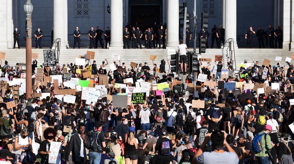 TOPSHOT - Police officers stand at the top of the stairs of City Hall as protesters rally to protest over the death of George Floyd under police custody, in Los Angeles, California, on June 3, 2020 - Derek Chauvin, the white Minneapolis police officer who kneeled on the neck of George Floyd, a black man who later died, will now be charged with second-degree murder, and his three colleagues will also face charges, court documents revealed on June 3. The May 25 death of George Floyd -- who had been accused of trying to buy cigarettes with a counterfeit bill -- has ignited protests across the United States over systemic racism and police brutality. (Photo by Frederic J. BROWN / AFP) (Photo by FREDERIC J. BROWN/AFP via Getty Images)