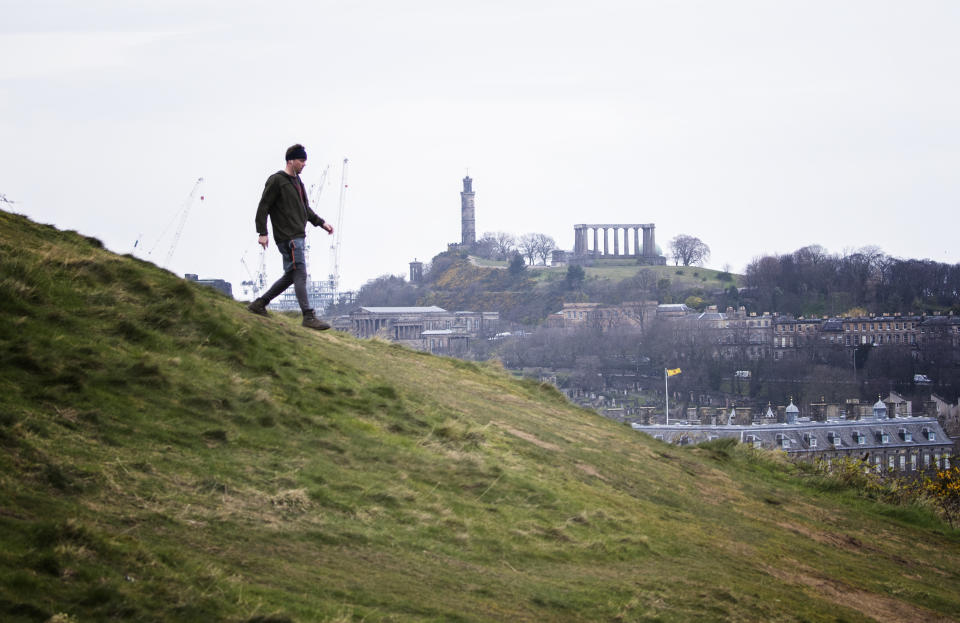 A man walks in Holyrood Park, Edinburgh, the day after Prime Minister Boris Johnson put the UK in lockdown to help curb the spread of the coronavirus.