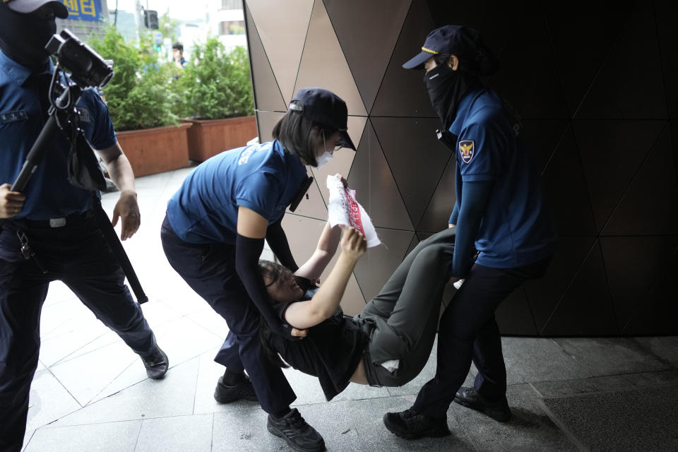 A South Korean student is detained by police officers as they attempt to enter to Japanese Embassy to protest denouncing to release treated radioactive water into the sea from the damaged Fukushima nuclear power plant, at a building which houses Japanese Embassy, in Seoul, South Korea, Thursday, Aug. 24, 2023. The operator of the tsunami-wrecked Fukushima Daiichi nuclear power plant says it has begun releasing its first batch of treated radioactive water into the Pacific Ocean — a controversial step, but a milestone for Japan's battle with the growing radioactive water stockpile. (AP Photo/Lee Jin-man)