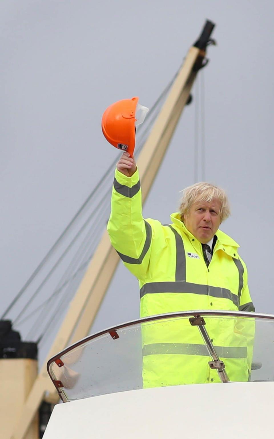 Hard-hat at the ready: Boris Johnson waves from a boat on the River Tees - AP Pool