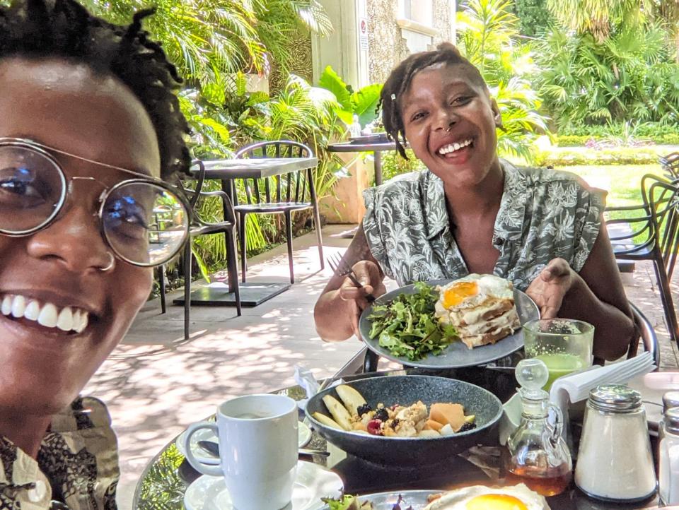 Amber and her partner posing with their food at an outdoor table