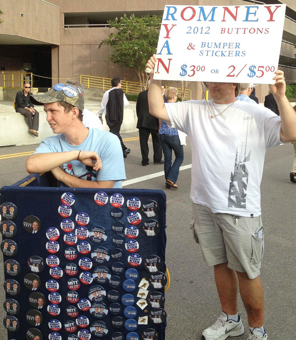 Michael Kirever, left, and Brian Judge, sell buttons of Republican presidential nominee Mitt Romney outside the Republican National Convention on Wednesday, Aug. 29, 2012, in Tampa, Fla. While buttons are seen at the convention, they are far from ubiquitous, and the days when delegates were littered with partisan messages from seemingly head to toe appear to be long past. (AP Photo/Peter Prengaman)