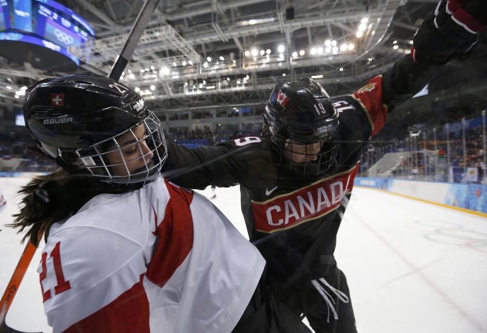 Canada's Jenner battles with Switzerland's Benz during the first period of their women's ice hockey game at the Sochi 2014 Sochi Winter Olympics