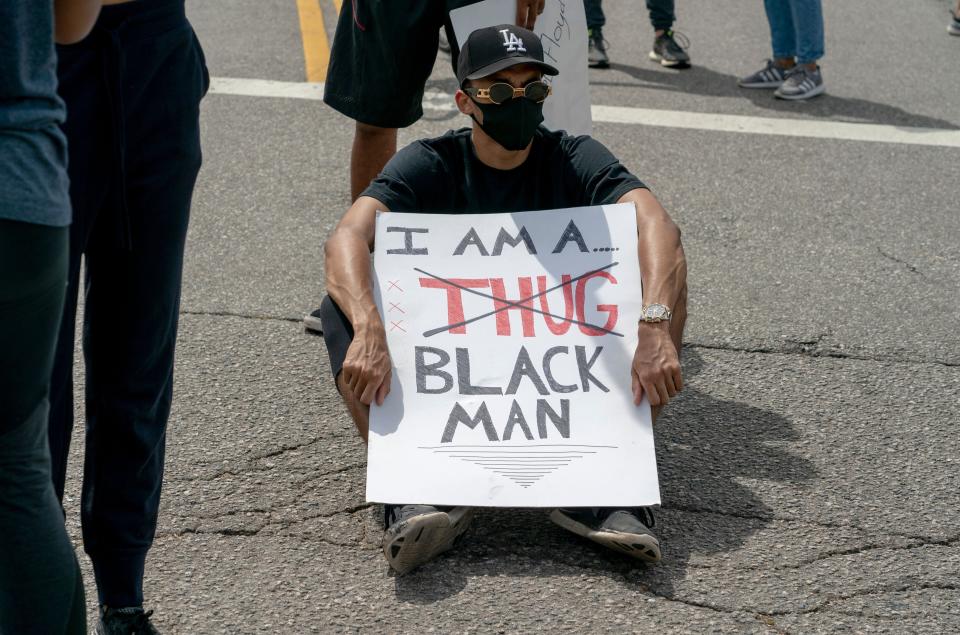 <i>A seated protester holds a sign during a June 2 demonstration in Los Angeles over the death of George Floyd.</i>