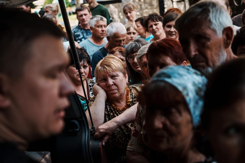 Residents in a residential compound wait for supplies to be given out by police officers