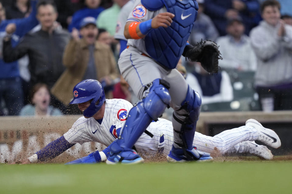 Chicago Cubs' Nico Hoerner scores behind New York Mets catcher Francisco Alvarez off Dansby Swanson's double during the third inning of a baseball game Wednesday, May 24, 2023, in Chicago. (AP Photo/Charles Rex Arbogast)