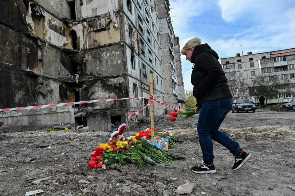A woman lays flowers in front of a damaged multistory residential building, where a Russian strike killed 23 people, in Uman (AFP via Getty Images)