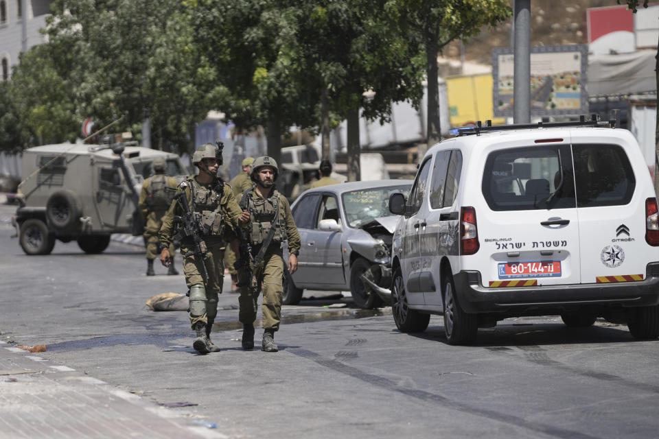 Israeli soldiers work at the site of an alleged car-ramming attack near Beit Hagai, a Jewish settlement in the hills south of the large Palestinian city of Hebron, Wednesday, Aug. 30, 2023. The Israeli military said security forces shot the Palestinian driver as he accelerated toward a military post. A soldier struck by the car was evacuated to a nearby hospital for treatment. There was no immediate word on the condition of the suspected Palestinian assailant. (AP Photo/Mahmoud Illean)