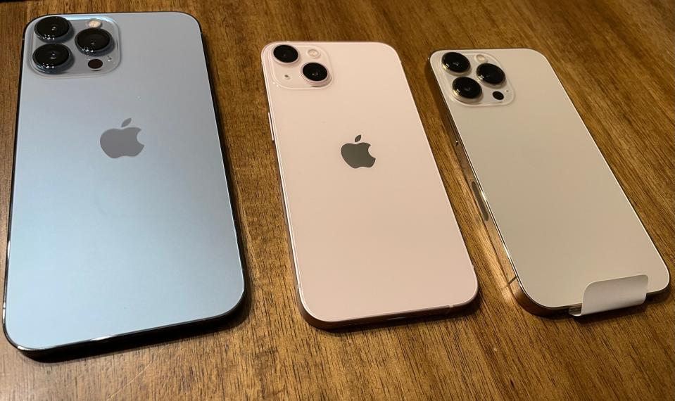 From left: the iPhone 13 Pro Max in sierra blue, the iPhone 13 in pink, and the iPhone 13 Pro in gold.