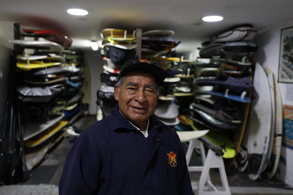 In this July 26, 2019 photo, Victor "Mamico" Curo, 79, stands amidst the thousands of surfboards he tends in the storage room named after him for his more than 60 years of service, at Club Waikiki in Lima, Peru. Surfing is a way of life in Peru, which has been called the Hawaii of Latin America. (AP Photo/Rebecca Blackwell)