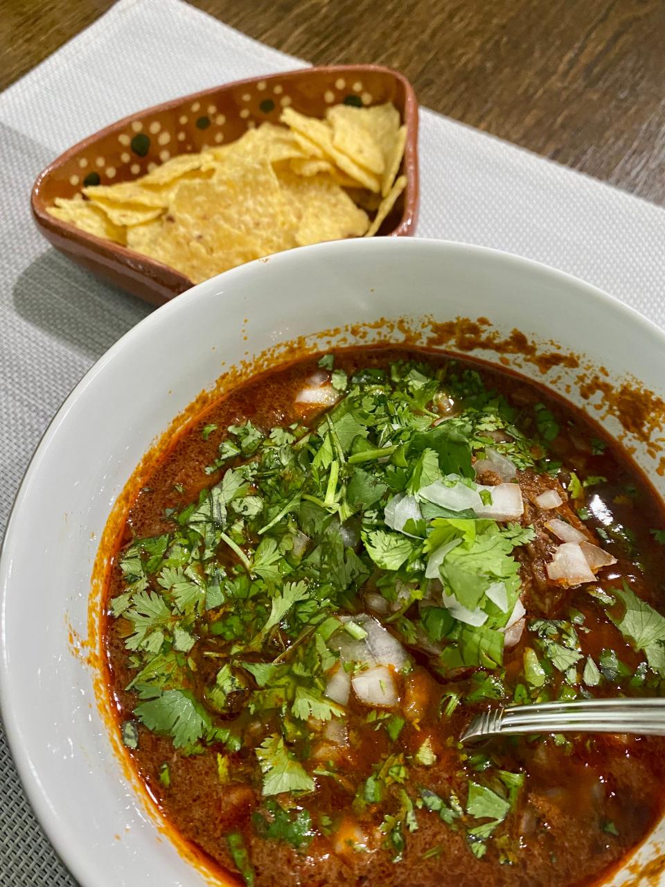 Bowl of birria with a side of tortilla chips.