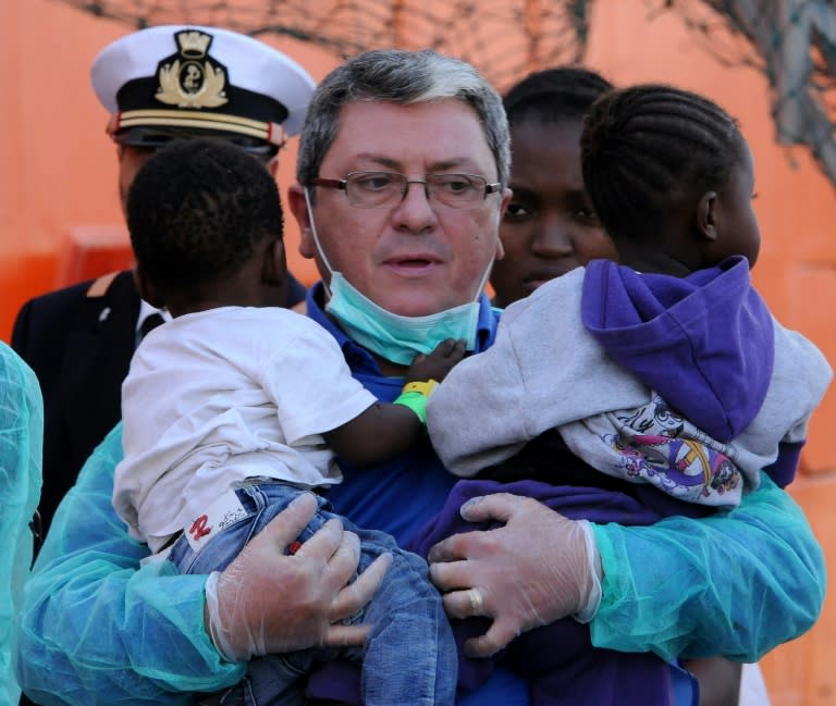 A rescuer holds two young children as migrants disembark from the Siem Pilot on October 24, 2016 in Palermo after rescue operations