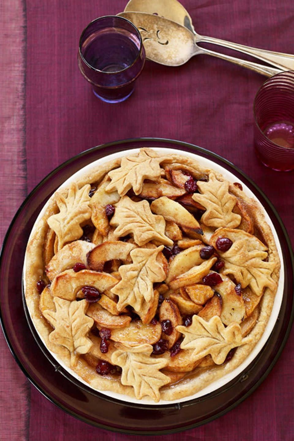 fall apple cranberry pie in a white pie dish with pie crust leaves on top