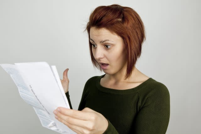 Shocked woman with wide open mouth receives credit card statement