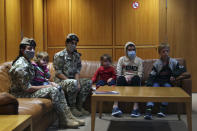 Members of the Lebanese General Security forces sit with Albanian children during an operation to take them back home to Albania from al-Hol, northern Syria, at the Rafik Hariri International Airport in Beirut, Lebanon, Tuesday, Oct. 27, 2020. The repatriation of four children and a woman related to Albanian nationals who joined Islamic extremist groups in Syria "is a great step" to be followed by more repatriations, Albania's prime minister said Tuesday. (AP Photo/Bilal Hussein)