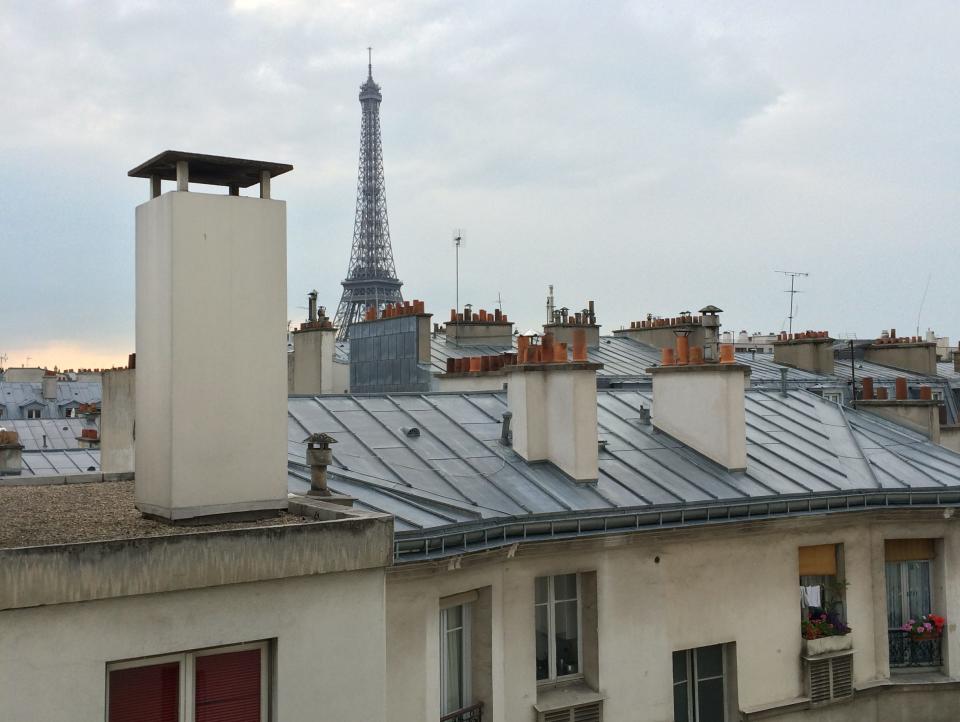 A view of the Eiffel Tower over the rooftop of a building.