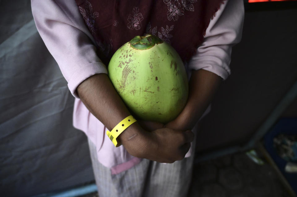 N, a 12-year-old ethnic Rohingya refugee identified by The Associated Press with only an initial, because she is a sexual assault survivor, holds a coconut ahead of breaking her Ramadan fast at a temporary shelter in Meulaboh, Indonesia, on Wednesday, April 3, 2024. N was forced to leave behind her family when she fled Bangladesh on a boat packed with other Rohingya refugees. She hoped to make it to Malaysia, where she'd been promised as a child bride to a man she'd never met. (AP Photo/Reza Saifullah)