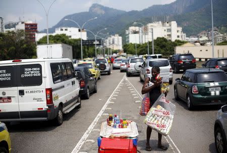 A street vendor holds goods for sale among cars during a traffic jam in Rio de Janeiro March 19, 2015. REUTERS/Ricardo Moraes