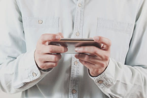 A man holding a mobile phone as if it were a game controller.