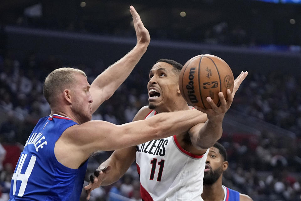 Portland Trail Blazers guard Malcolm Brogdon, center, shoots as Los Angeles Clippers center Mason Plumlee, left, and forward Paul George defend during the first half of an NBA basketball game Wednesday, Oct. 25, 2023, in Los Angeles. (AP Photo/Mark J. Terrill)