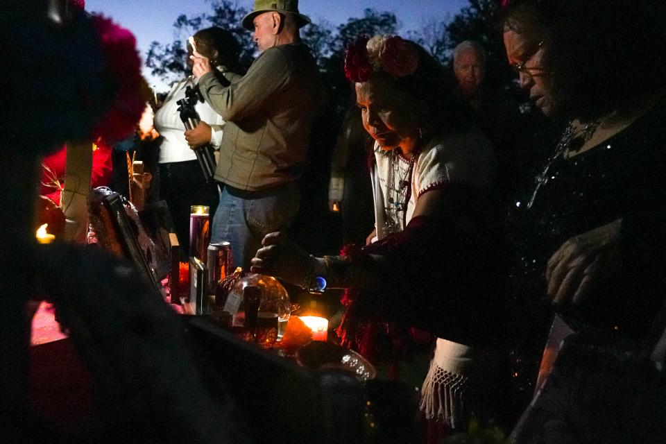 Hermelinda Zamarripa places an offering on her extended family's ofrenda, or altar, during the Alma y Corazon ceremony Thursday at Oakwood Cemetery.