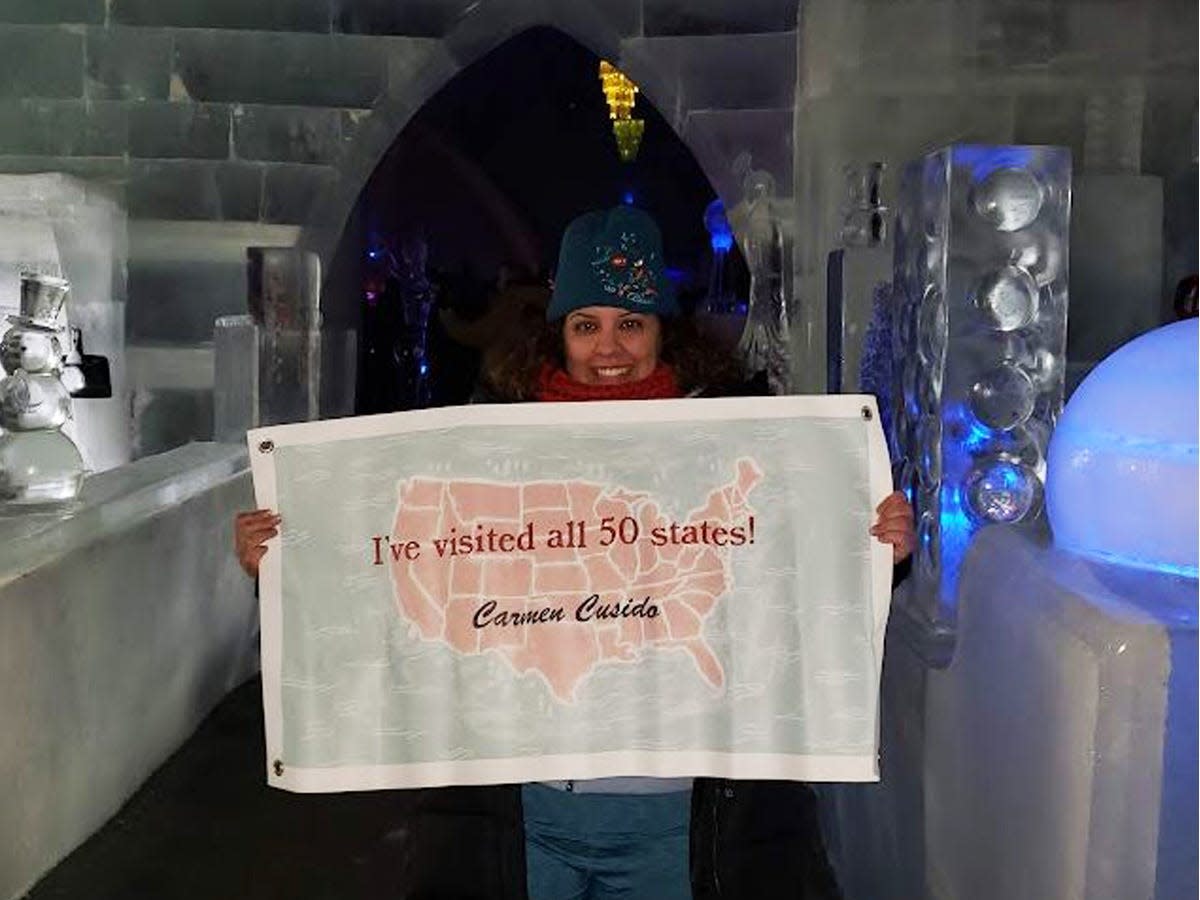 Carmen in Alaska holding up sign that says "I've been to all 50 states"