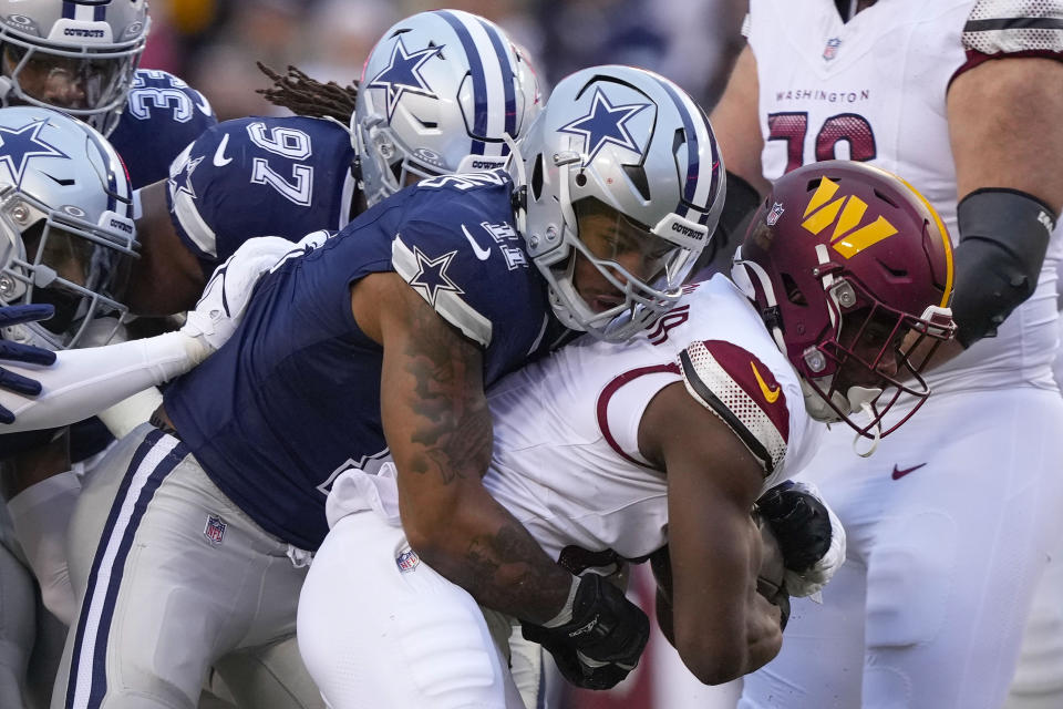 Washington Commanders running back Brian Robinson Jr. (8) is tackled by Dallas Cowboys defensive tackle Osa Odighizuwa (97) and linebacker Micah Parsons (11) during the first half of an NFL football game, Sunday, Jan. 7, 2024, in Landover, Md. (AP Photo/Susan Walsh)