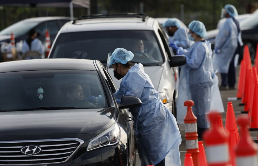 NORWALK, CA - JANUARY 12, 2022: Health care workers administer COVID-19 tests at the drive-thru mega testing site on the east side of the Norwalk/Santa Fe Springs Metrolink Station on January 12, 2022 in Norwalk, California.(Gina Ferazzi / Los Angeles Times)