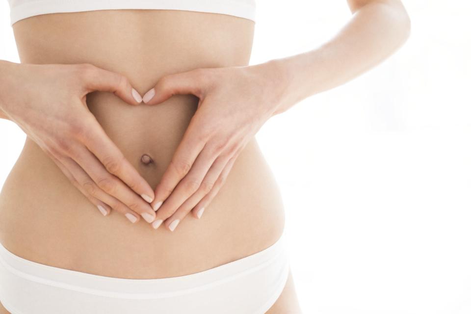 Woman with hands in heart shape on stomach