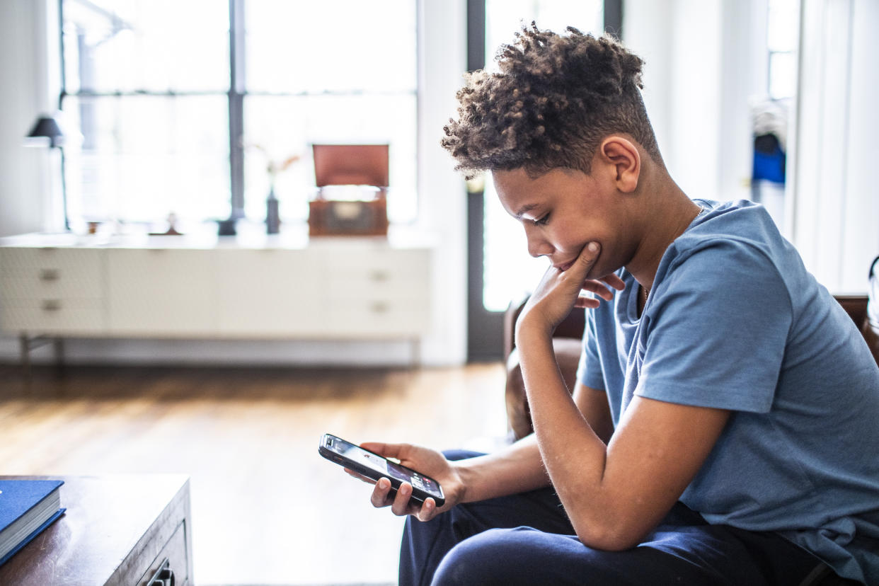 Teenage boy using smartphone in residential living room