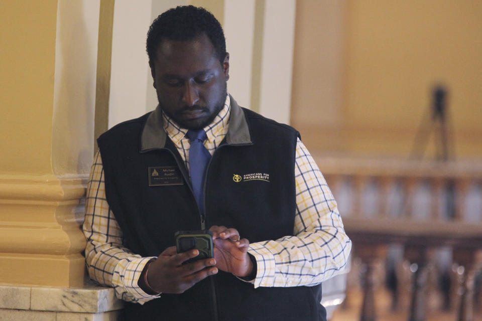 Michael Austin, a Kansas economist and a lobbyist for the free-market, small-government group Americans for Prosperity, monitors a Senate debate on a proposal aimed at luring the Super Bowl champion Kansas City Chiefs and professional baseball's Kansas City Royals from Missouri, Tuesday, June 18, 2024, outside the Senate chamber at the Statehouse in Topeka, Kansas. Austin and AFP oppose the proposal, which would allow the state to issue bonds to help the teams finance new stadiums in Kansas. (AP Photo/John Hanna)