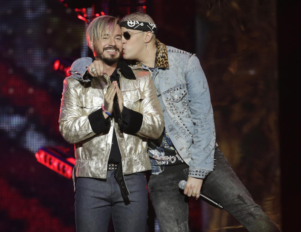 FILE - Singer Bad Bunny, right, kisses J Balvin, after they performed together at the Latin Billboard Awards in Coral Gables, Fla. on April 27, 2017. Balvin has a chance of winning his first album of the year prize at the Latin Grammy Awards with his fifth solo album “Colores” and “Oasis,” his collaborative project with Bad Bunny. (AP Photo/Lynne Sladky, File)