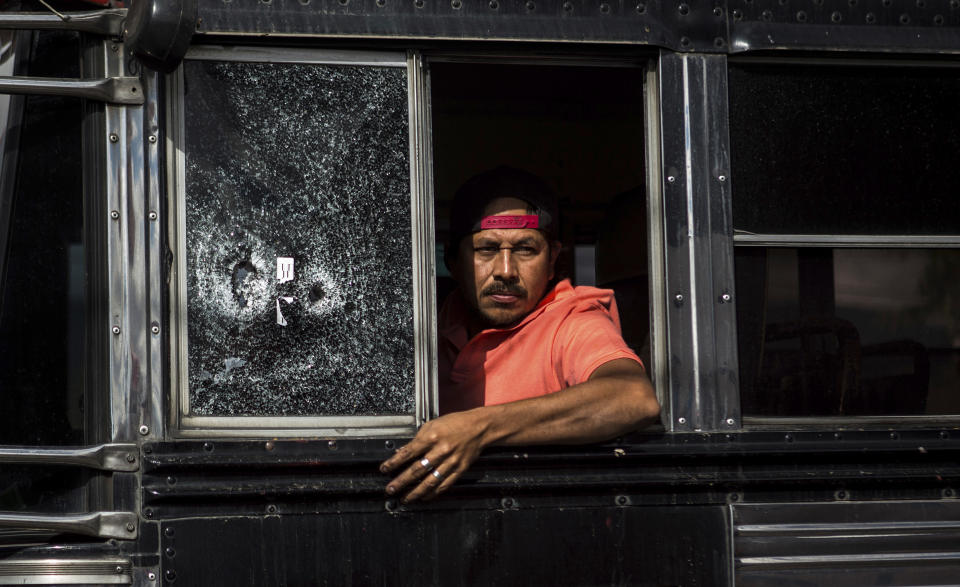 A bus driver peers from his window, which he said was shot a few weeks ago, as he drives slowly through a security checkpoint in the El Milagro area of the Mixco municipality on the outskirts of Guatemala City, Friday, Jan. 17, 2020. Guatemala's new president announced a state of alert for two municipalities with high crime rates to combat gang activity Friday, a measure that allows the deployment of military troops. (AP Photo/Oliver de Ros)