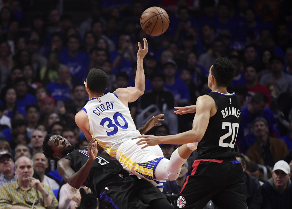 Golden State Warriors guard Stephen Curry, center, runs into Los Angeles Clippers guard Patrick Beverley, left, as he shoots while guard Landry Shamet watches during the first half in Game 4 of a first-round NBA basketball playoff series Sunday, April 21, 2019, in Los Angeles. (AP Photo/Mark J. Terrill)