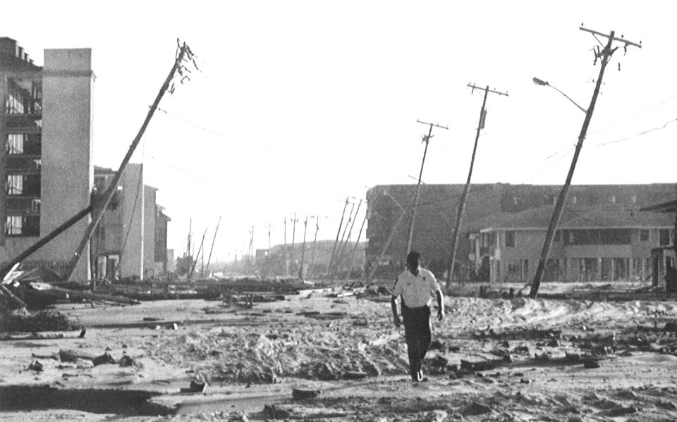 FILE- In this Sept. 23, 1989 file photo, Horry County police officer Jamie Thompkins takes a walk down Ocean Front Road in Garden City Beach, S.C., after Hurricane Hugo hit the town and left heavy damage behind. The Category 4 storm, caused $9.5 billion in damage. (AP Photo/Bob Jordan, File)