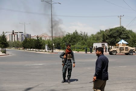 Afghan policemen stand guard near the site of a blast and gunfire in Kabul