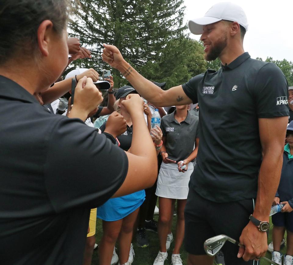 Stephen Curry fist bumps Underrated Golf tour players as they gather around him on the 18th hole of the South Course at Firestone Country Club in Akron.
