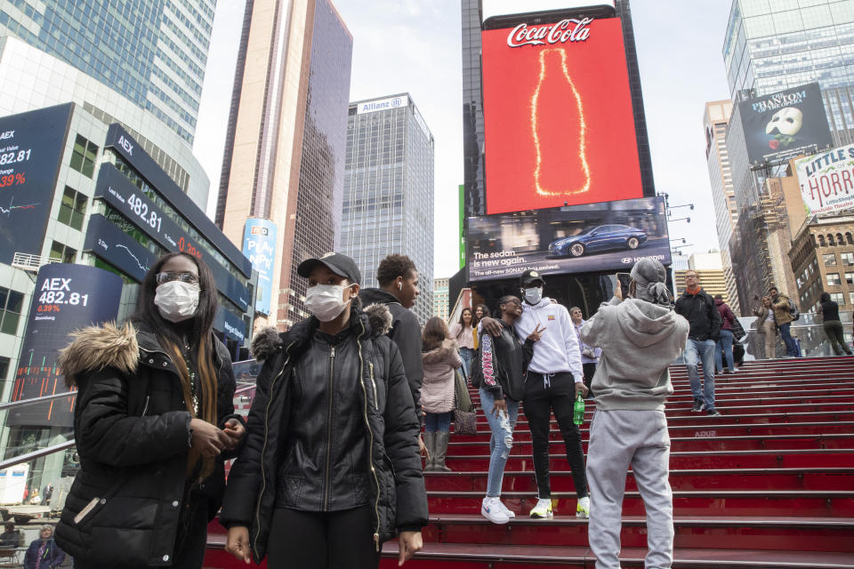 A group of visitors from Philadelphia wear masks as a precaution to the coronavirus, Wednesday, March 11, 2020, in New York's Times Square. New York Gov. Andrew Cuomo said Wednesday he will ask business owners to stagger their employees' work shifts or let them work from home to reduce potential coronavirus exposures. (AP Photo/Mary Altaffer)
