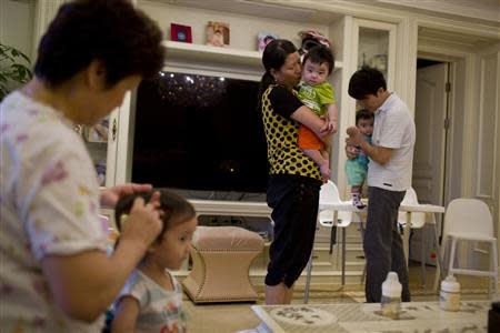 A nanny holds a child of Tony Jiang (back R) at his house in Shanghai September 16, 2013. REUTERS/Aly Song