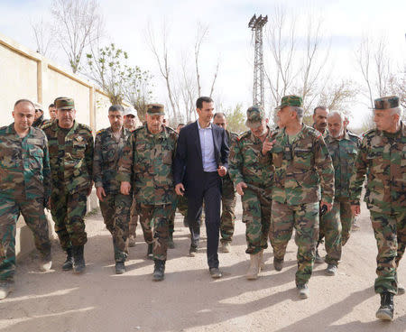 Syrian President Bashar al-Assad walks with Syrian army soldiers in eastern Ghouta, Syria, March 18, 2018. SANA/Handout via REUTERS