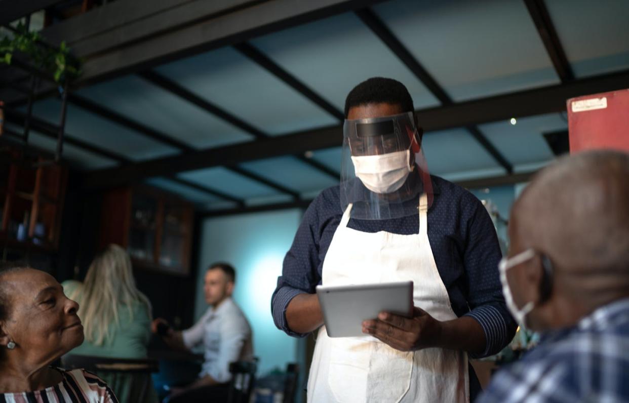 <span class="caption">People who dine out after the CDC recently changed mask guidelines are counting on the honor system. </span> <span class="attribution"><a class="link " href="https://www.gettyimages.com/detail/photo/waiter-taking-clients-order-using-a-digital-tablet-royalty-free-image/1255797795?adppopup=true" rel="nofollow noopener" target="_blank" data-ylk="slk:FG Trade/Getty Images;elm:context_link;itc:0;sec:content-canvas">FG Trade/Getty Images</a></span>
