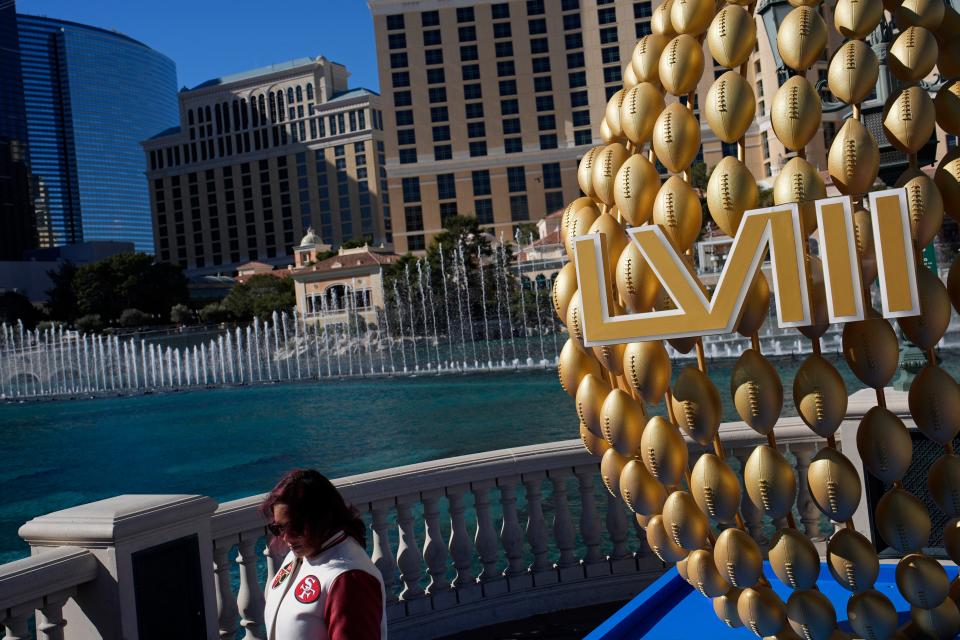 A fan walks by signage for the Super Bowl as the Bellagio fountains erupt along the Las Vegas Strip ahead of the Super Bowl 58 NFL football game Saturday, Feb. 10, 2024, in Las Vegas.