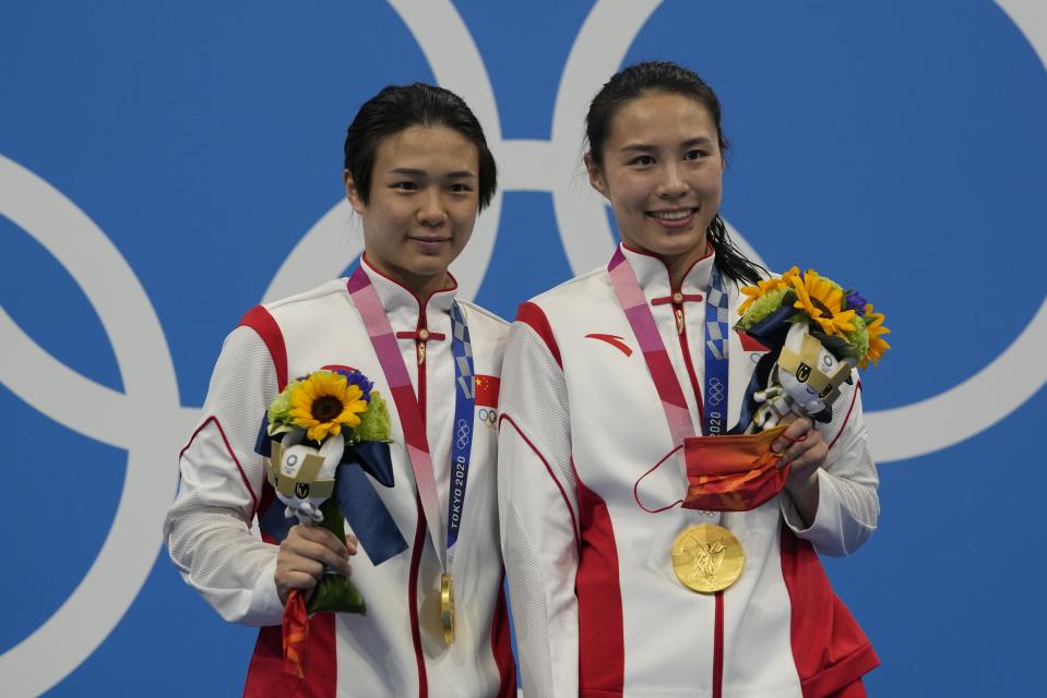 Shi Tingmao and Wang Han pose for a photo after winning gold medals during the Women's Synchronized 3m Springboard Final at the Tokyo Aquatics Centre at the 2020 Summer Olympics, Sunday, July 25, 2021, in Tokyo, Japan. (AP Photo/Dmitri Lovetsky)