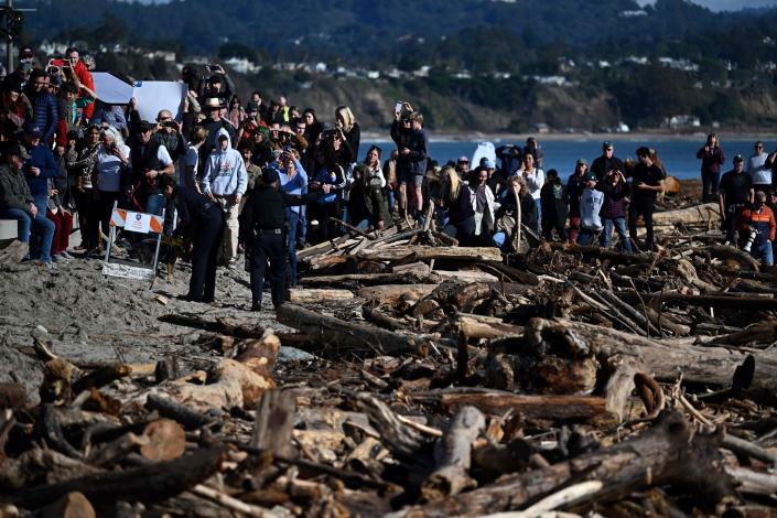 People look on as President Joe Biden surveys damage caused by recent heavy storms (AFP via Getty Images)