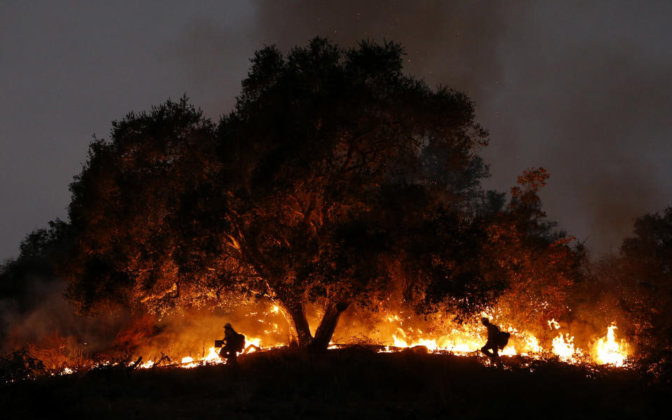 <p>Two firefighters work at a fire spot in Carpinteria, Calif., Dec. 11, 2017. (Photo: Li Ying/Xinhua via ZUMA Wire) </p>