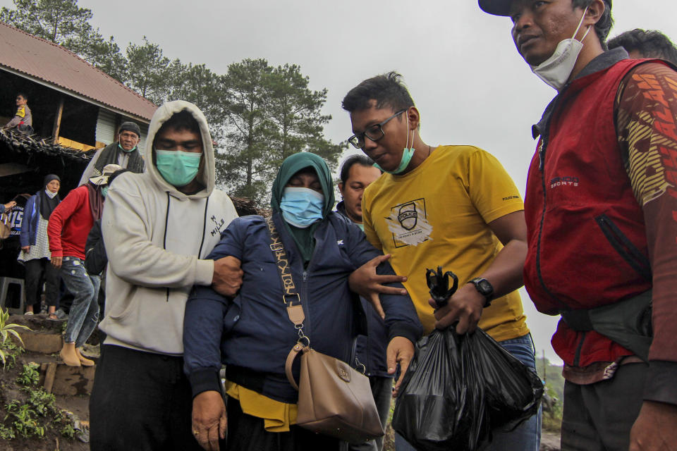 A relative of a victim of the eruption of Mount Marapi, center, is assisted to walk by family members as they wait for news on their loved ones at rescuers' base in Agam, West Sumatra, Indonesia, Tuesday, Dec. 5, 2023. Rescuers searching the hazardous slopes of the volcano found more bodies of climbers who were caught by a surprise weekend eruption, raising the number of confirmed dead to nearly two dozens, officials said Tuesday. (AP Photo/Ade Yuandha)