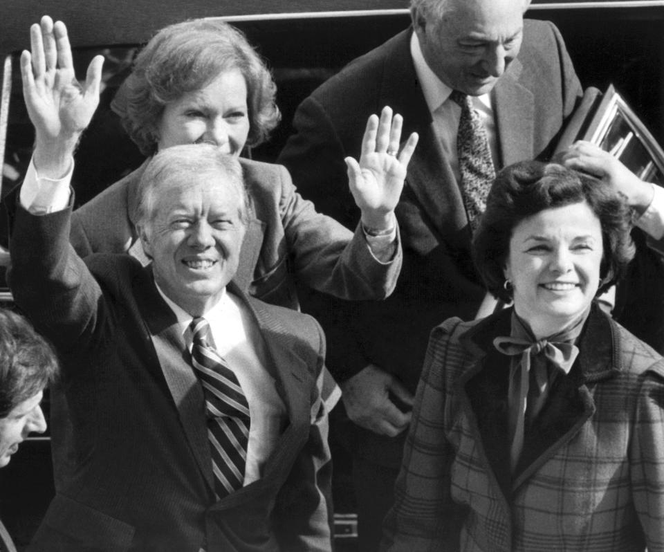 FILE - Former President Jimmy Carter and his wife, Rosalynn, back left, wave to photographers on the City Hall balcony as they arrived with San Francisco Mayor Dianne Feinstein, right, in San Francisco, Tuesday, Feb. 1, 1983. Carter's meeting with the mayor was canceled when a caller phoned in a routine bomb threat, the Secret Service said. (AP Photo/Eric Risberg, File)